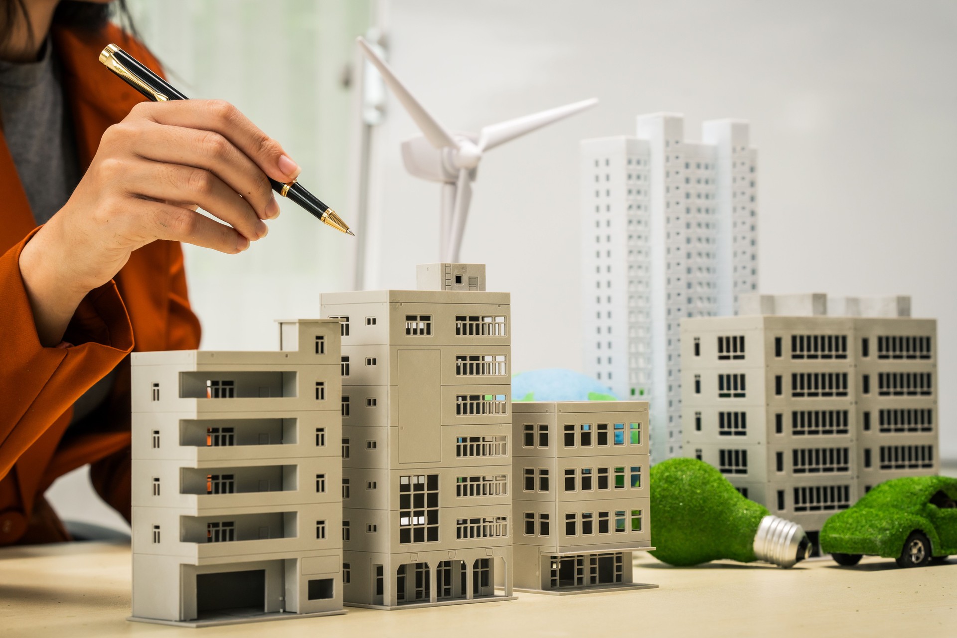 A businesswoman working at a desk in sustainable urban development, promoting eco-friendly futures with green condos and buildings, fostering a clean environment-friendly future.